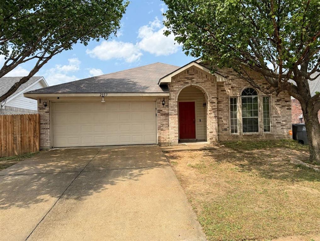 Brick exterior featuring an arched entryway, shingle roofing, multi-pane windows, and a concrete driveway Brick exterior featuring an arched entryway, shingle roofing, multi-pane windows, and a concrete driveway