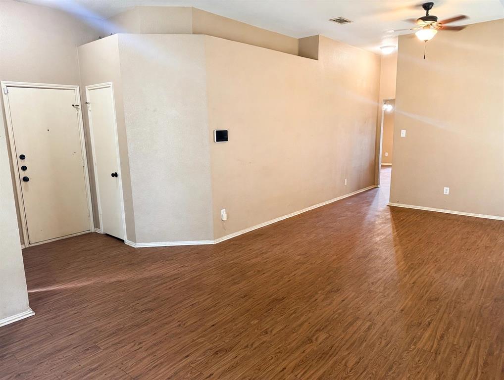 Interior space featuring wood-finish flooring, vaulted ceilings, and a ceiling fan with integrated lighting Interior space featuring wood-finish flooring, vaulted ceilings, and a ceiling fan with integrated lighting