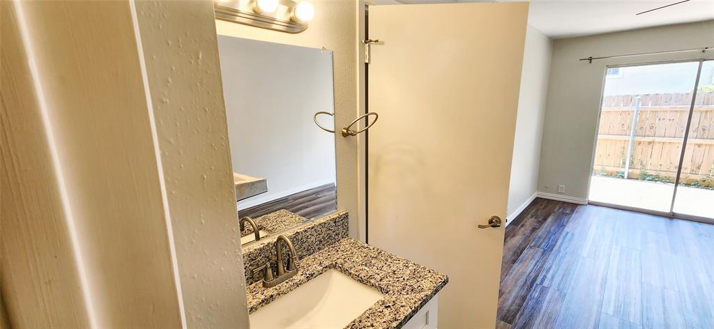 Bathroom vanity featuring a stone-composite countertop, undermount sink, and polished metal faucet with integrated mirror and overhead light fixture