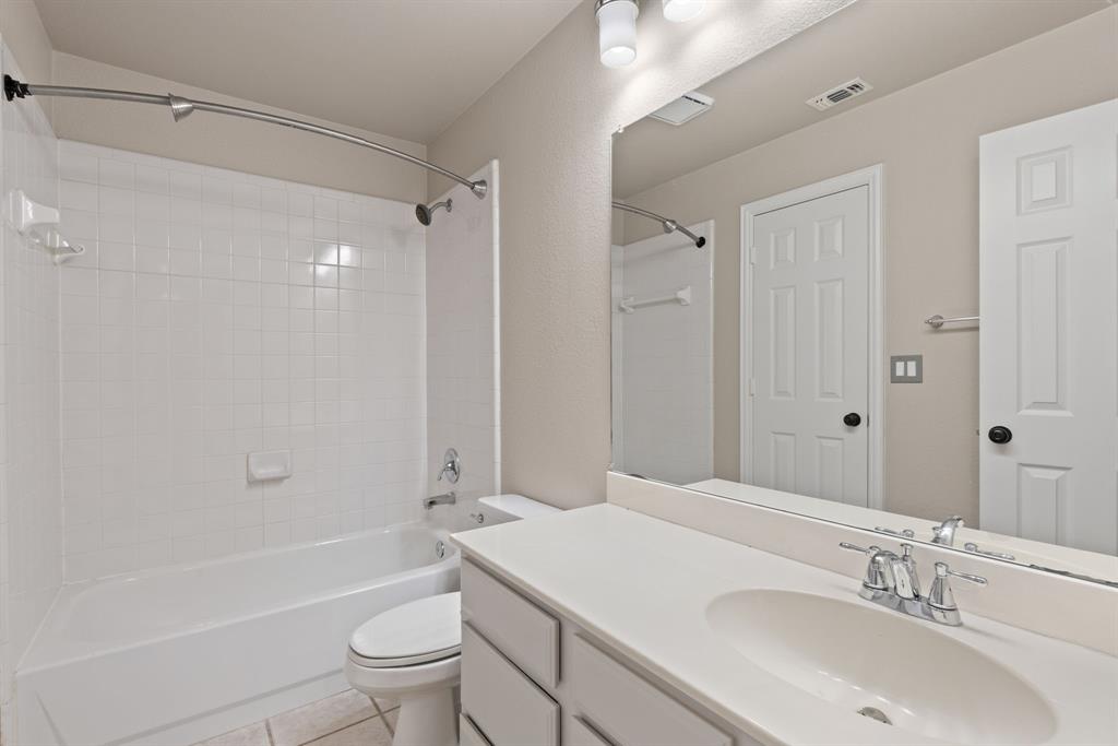 Full-width vanity with integrated sink, expansive wall-mounted mirror, white tile shower surround, curved shower rod, and two-panel interior door