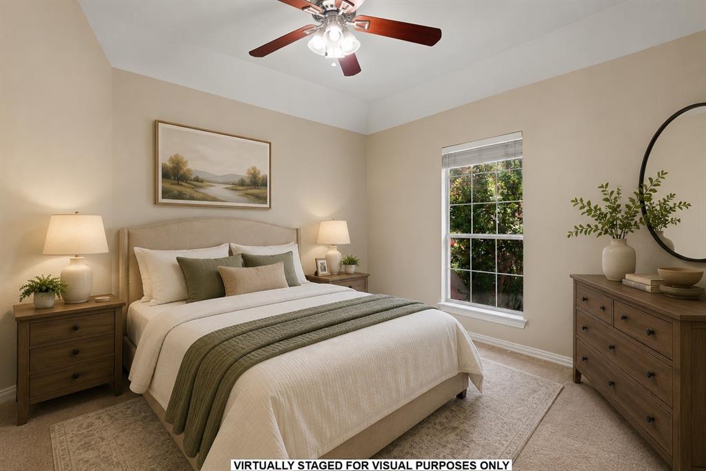 Room featuring a tray ceiling, neutral wall tones, carpeting, and a multi-blade ceiling fan with integrated lighting