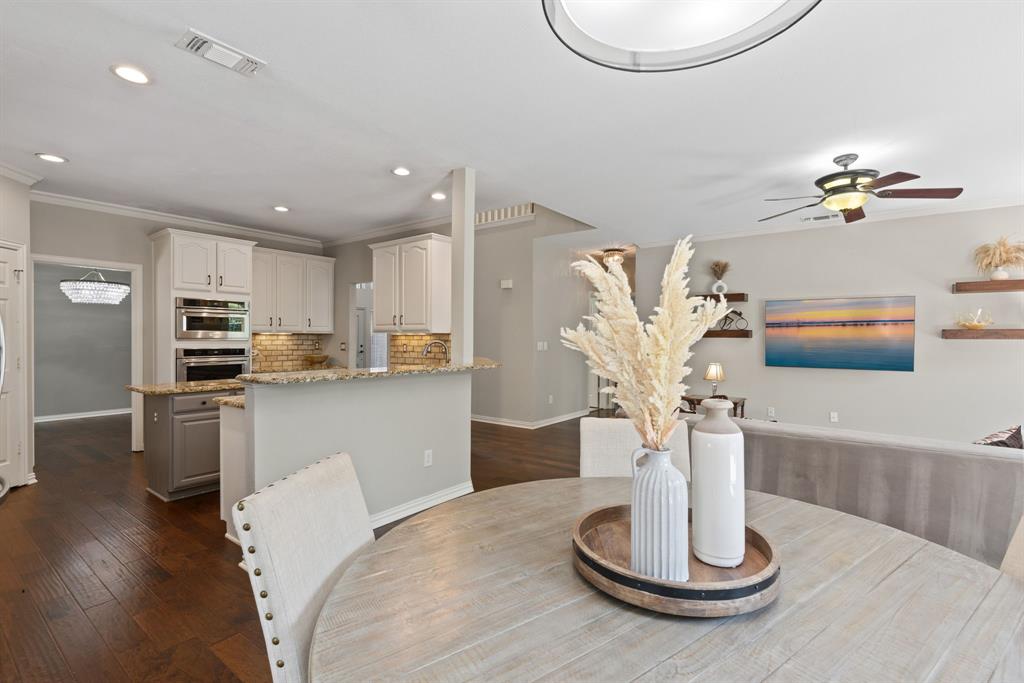 Kitchen featuring custom white cabinetry, built-in double ovens, stone countertops, and wood-finish flooring throughout the space, complemented by recessed lighting