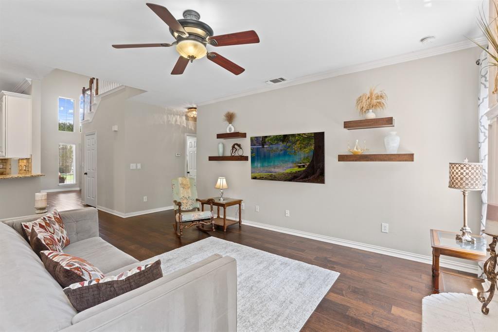 Wood-finish flooring, ceiling fan with integrated lighting, and wall-mounted wood shelving