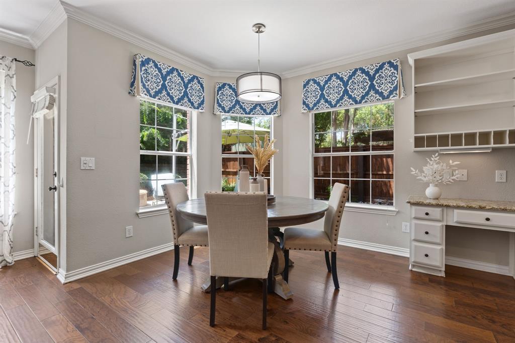 Bay window featuring divided-light windows, wood-finish flooring, built-in cabinetry with stone-surface desk, and a pendant light fixture