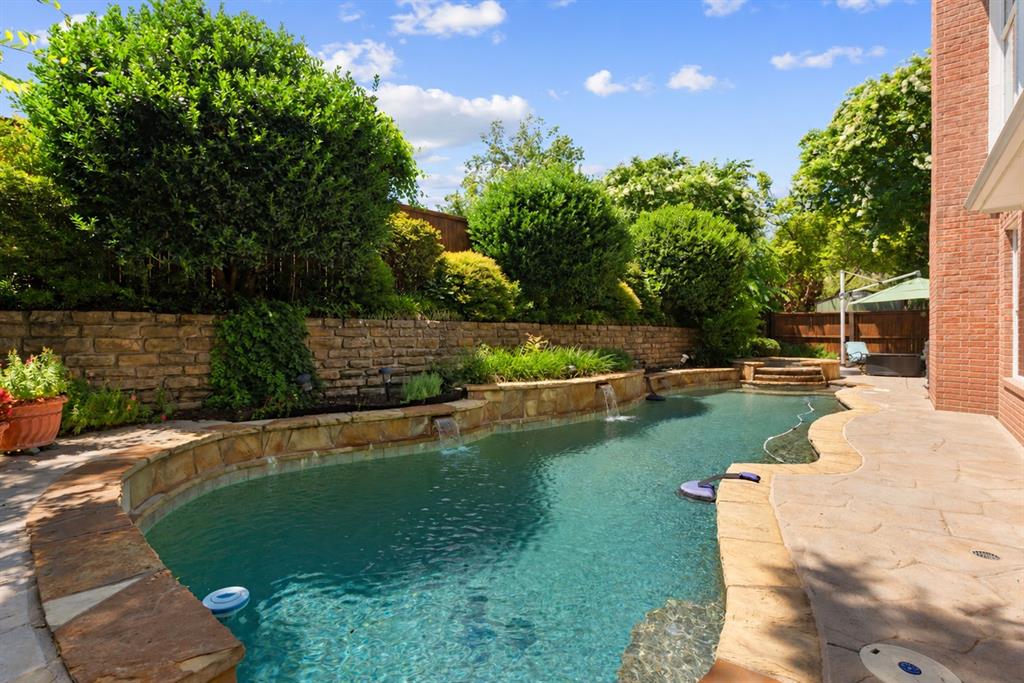 In-ground pool with stone coping, water features, flagstone patio, and tiered stone retaining walls