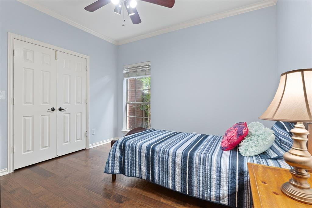 Wood-finish flooring, double-door closet with dark hardware, crown molding, and ceiling fan with integrated lighting