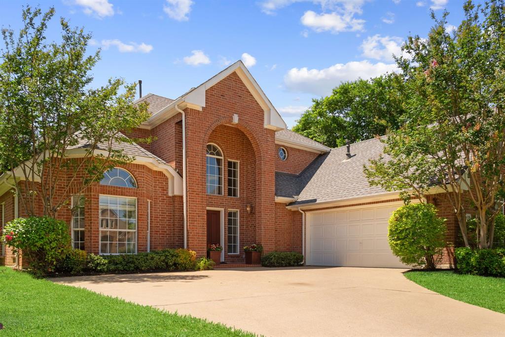 Traditional brick exterior featuring a prominent arched entryway, gabled roofline, multi-pane arched windows, and a multi-car garage