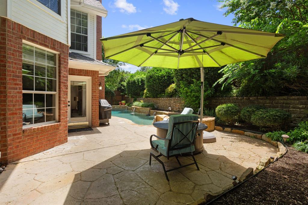 Flagstone patio featuring an in-ground pool, stacked stone retaining wall, and red brick exterior finish