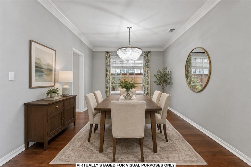 Dining area featuring wood-finish flooring, crown molding, and a crystal-accented chandelier Dining area featuring wood-finish flooring, crown molding, and a crystal-accented chandelier
