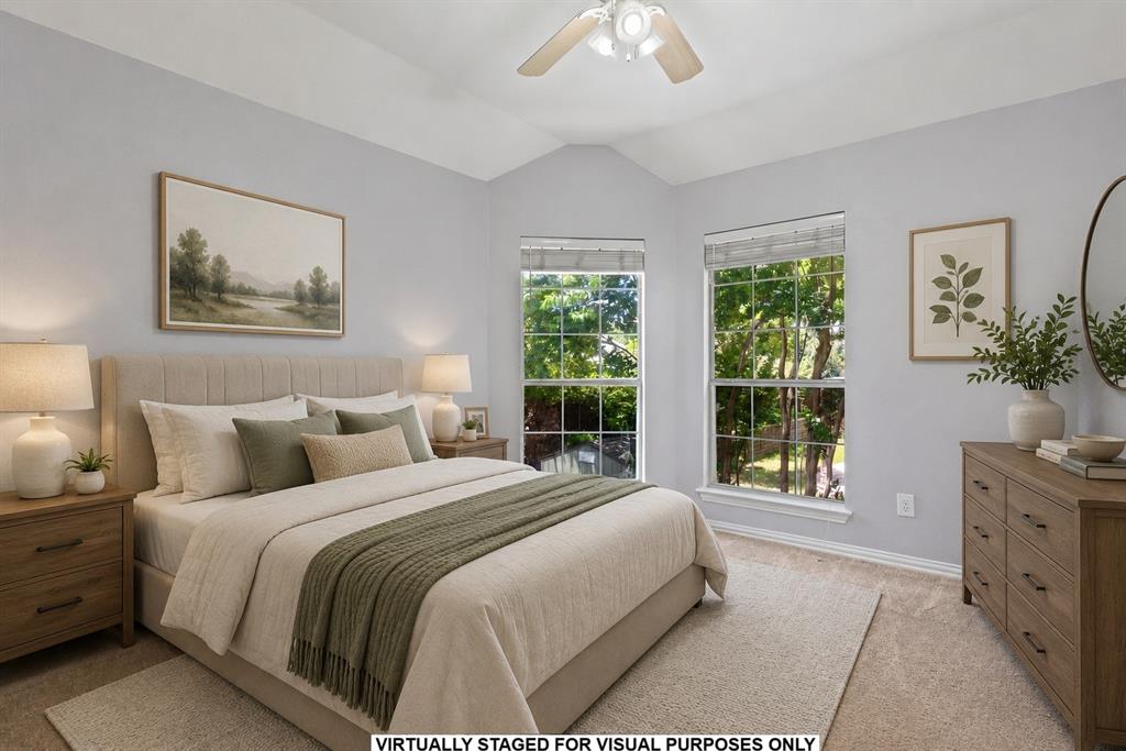 Vaulted ceiling featuring a central multi-blade ceiling fan, neutral wall tones, and tall multi-pane windows