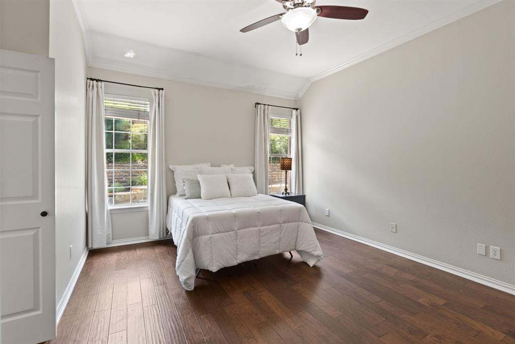Vaulted ceilings, wood-finish flooring, and dual double-hung windows with neutral wall-mounted hardware and integrated ceiling fan