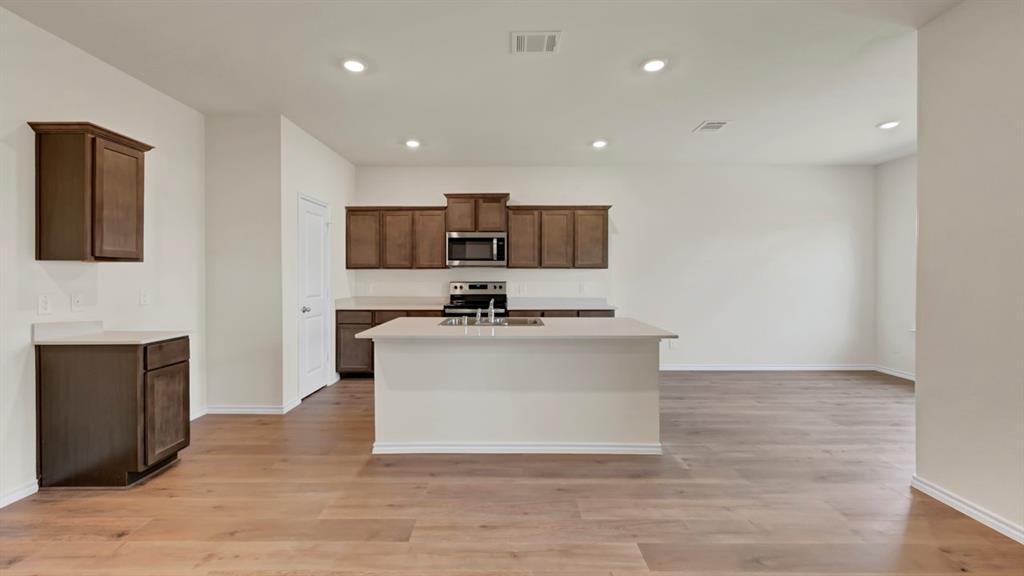 Expansive kitchen with an island, wood-finish flooring, recessed lighting, and dark wood cabinetry