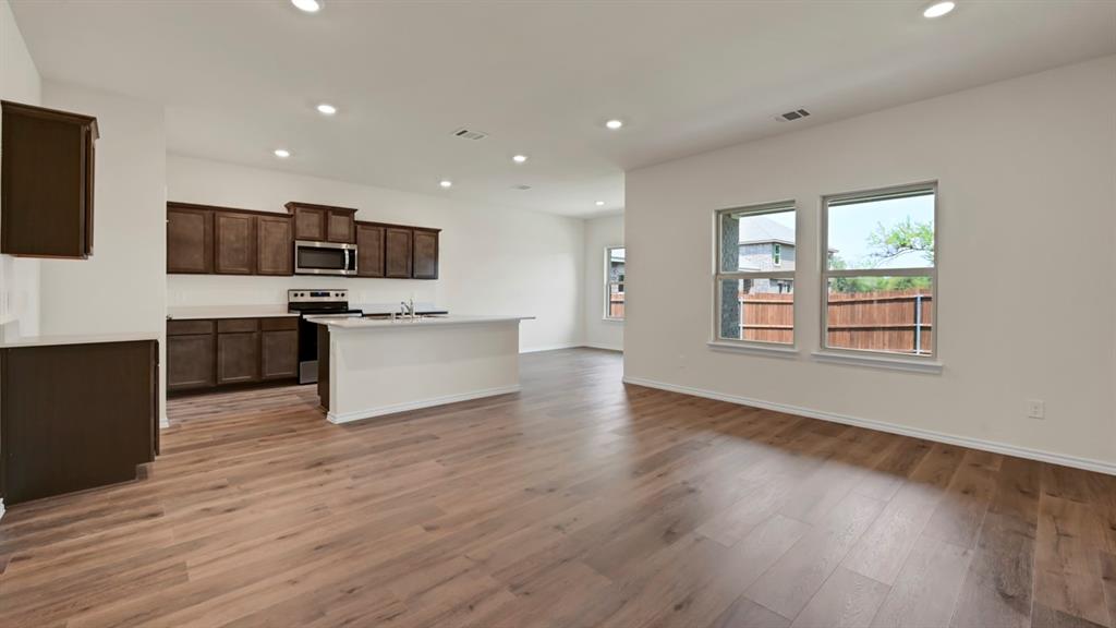 Open-concept living area with wood-finish flooring, recessed lighting, and multiple windows