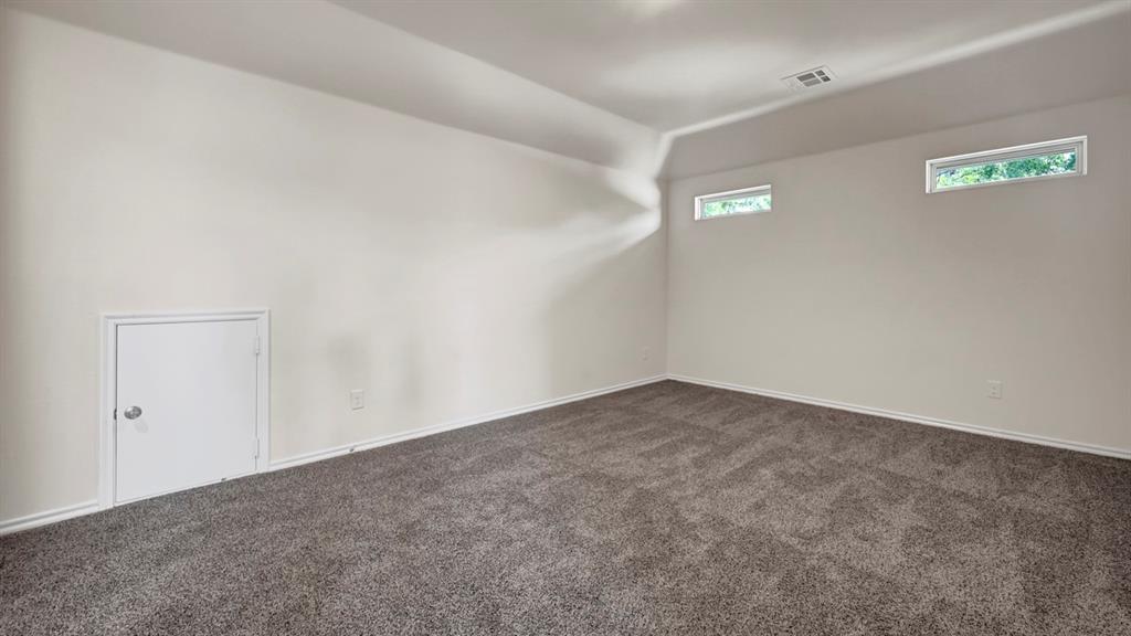 Carpeted flooring, vaulted ceiling, white walls, and two clerestory windows