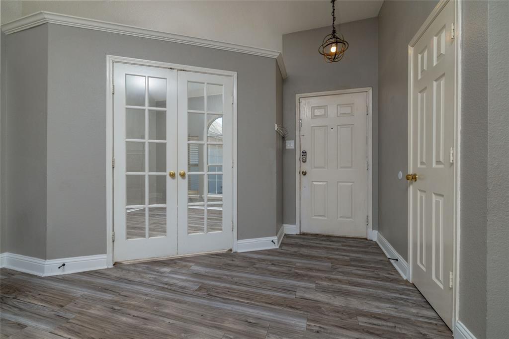 Entryway featuring wood-finish flooring, white paneled doors, dual glass-paneled French doors, and an orb-style pendant light fixture Entryway featuring wood-finish flooring, white paneled doors, dual glass-paneled French doors, and an orb-style pendant light fixture