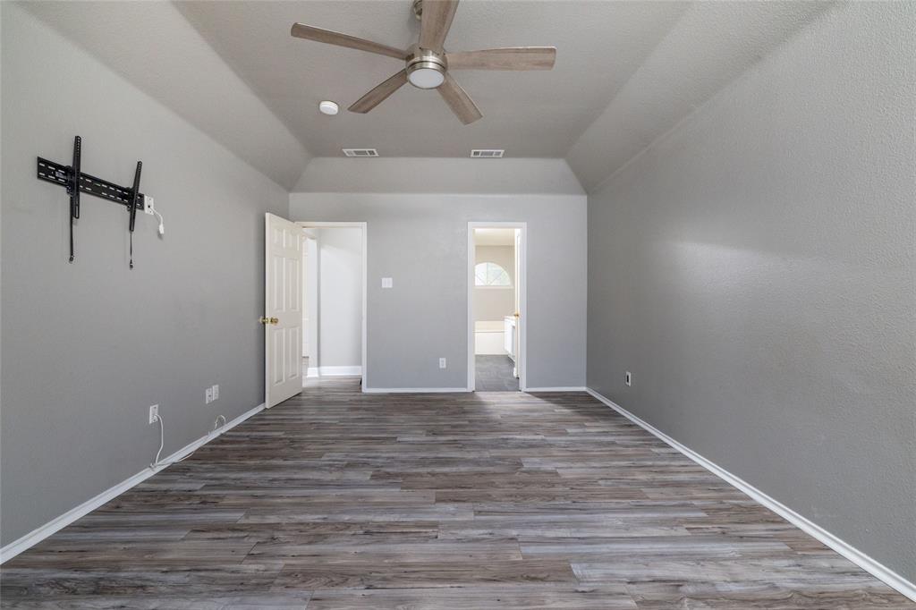 Tray ceiling, wood-finish flooring, and a multi-blade ceiling fan with integrated lighting