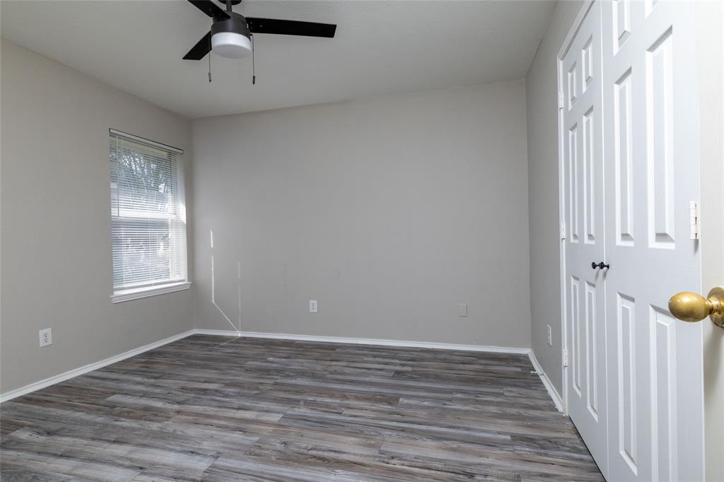 Neutral-toned walls paired with wood-finish flooring, a ceiling fan with integrated lighting, a dual-panel closet, and a single-hung window