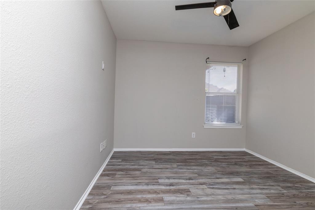 Neutral-toned room featuring wood-finish flooring, a single-light ceiling fan, and a window with integrated blinds