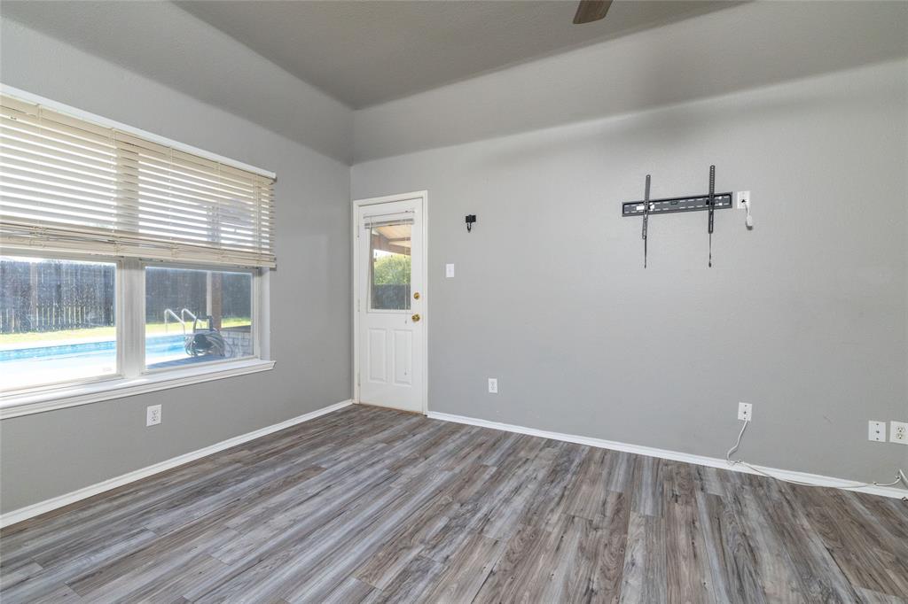 Interior space featuring wood-finish flooring, tray ceiling, large window with horizontal blinds, and exterior door with a glass insert
