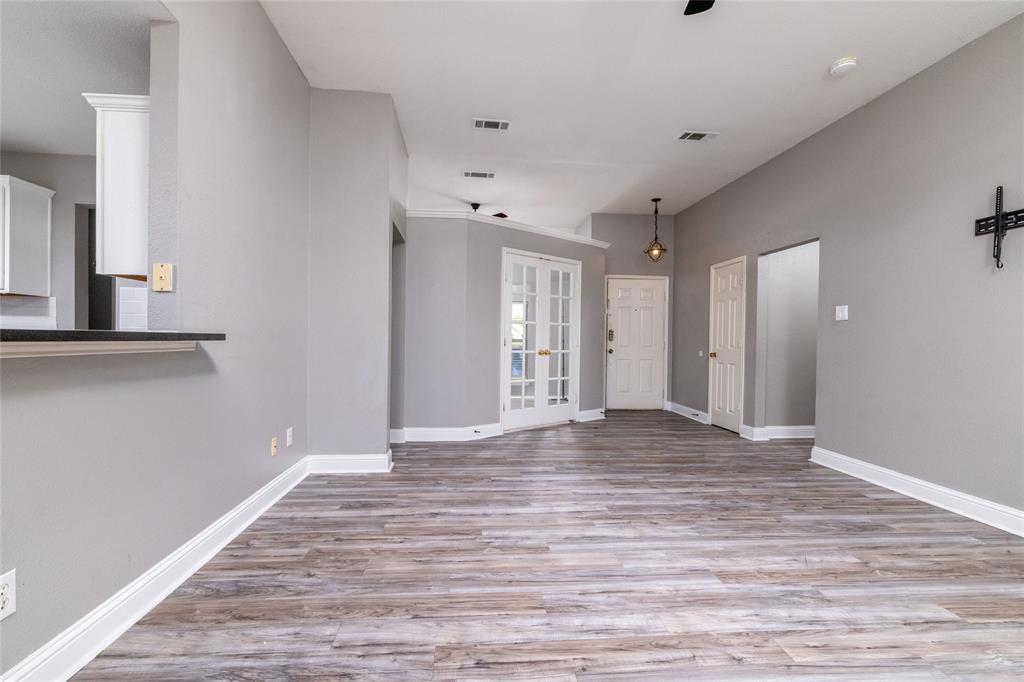 Open-concept interior featuring wood-finish flooring, recessed lighting, crown molding, double French doors, and a breakfast bar
