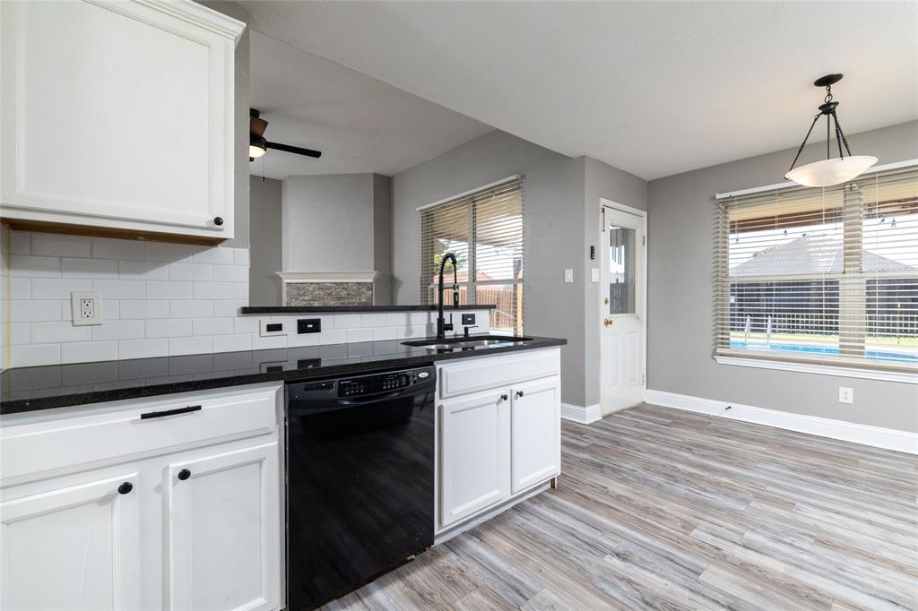 Kitchen featuring white shaker-style cabinetry, dark stone-finish countertops, white subway tile backsplash, matte black hardware, and wood-finish flooring