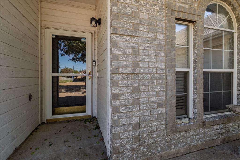 Covered entryway featuring a brick facade, horizontal siding, and a window with an arched transom Covered entryway featuring a brick facade, horizontal siding, and a window with an arched transom