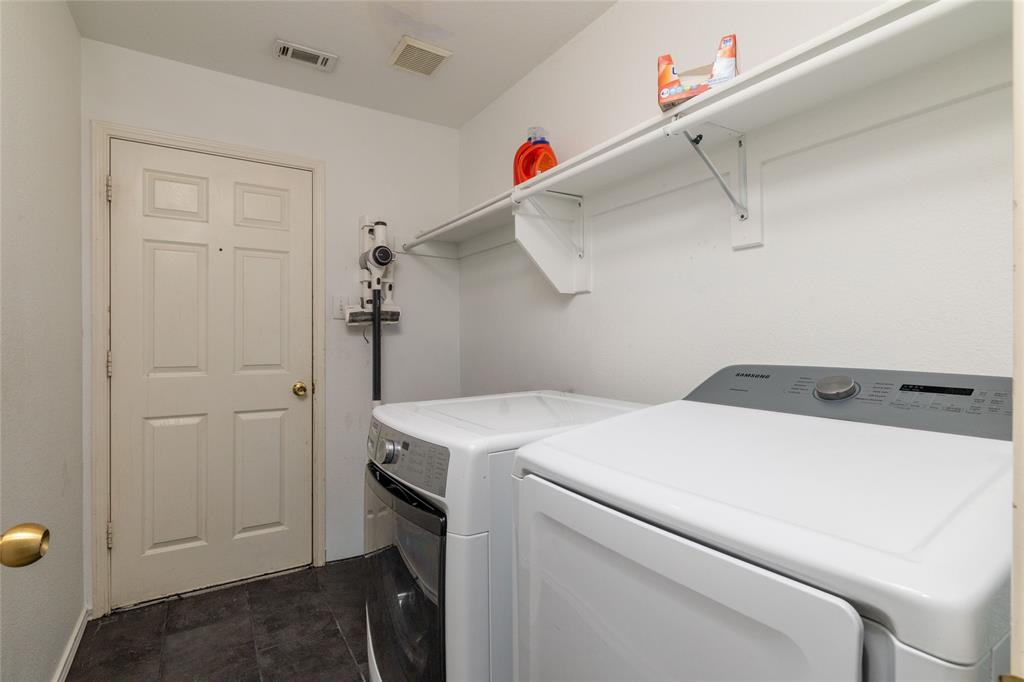 Laundry area featuring dark tile flooring, a six-panel door, and integrated wall-mounted shelving