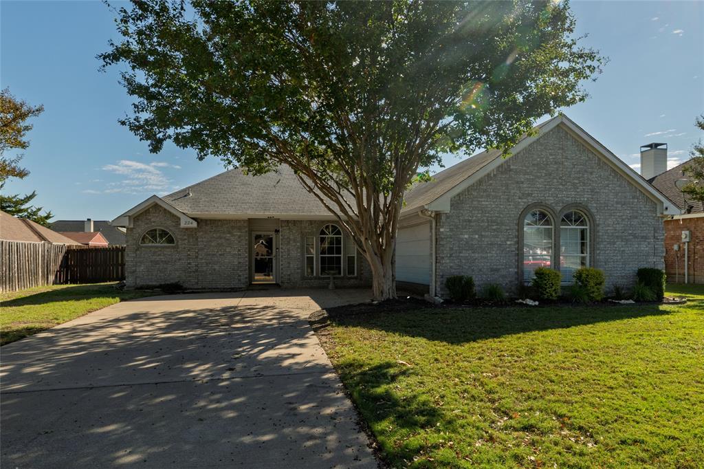 Single-story brick exterior featuring an arched window, a concrete driveway, a front-facing gable roof, and an attached garage