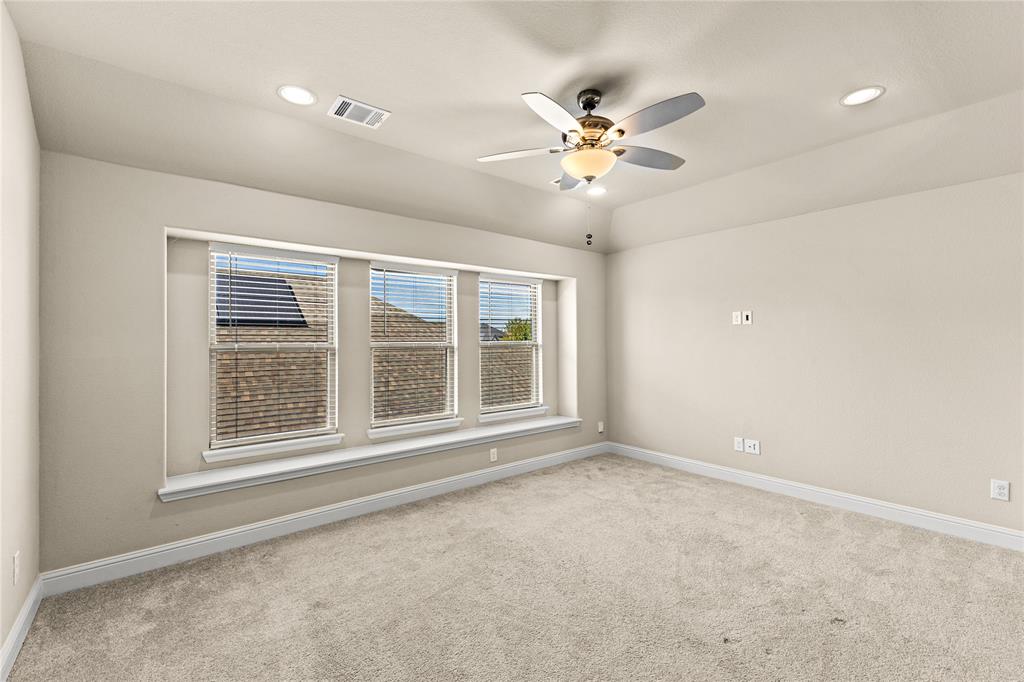 Tray ceiling with a central multi-blade ceiling fan, recessed lighting, and a triple-window configuration featuring a built-in window seat
