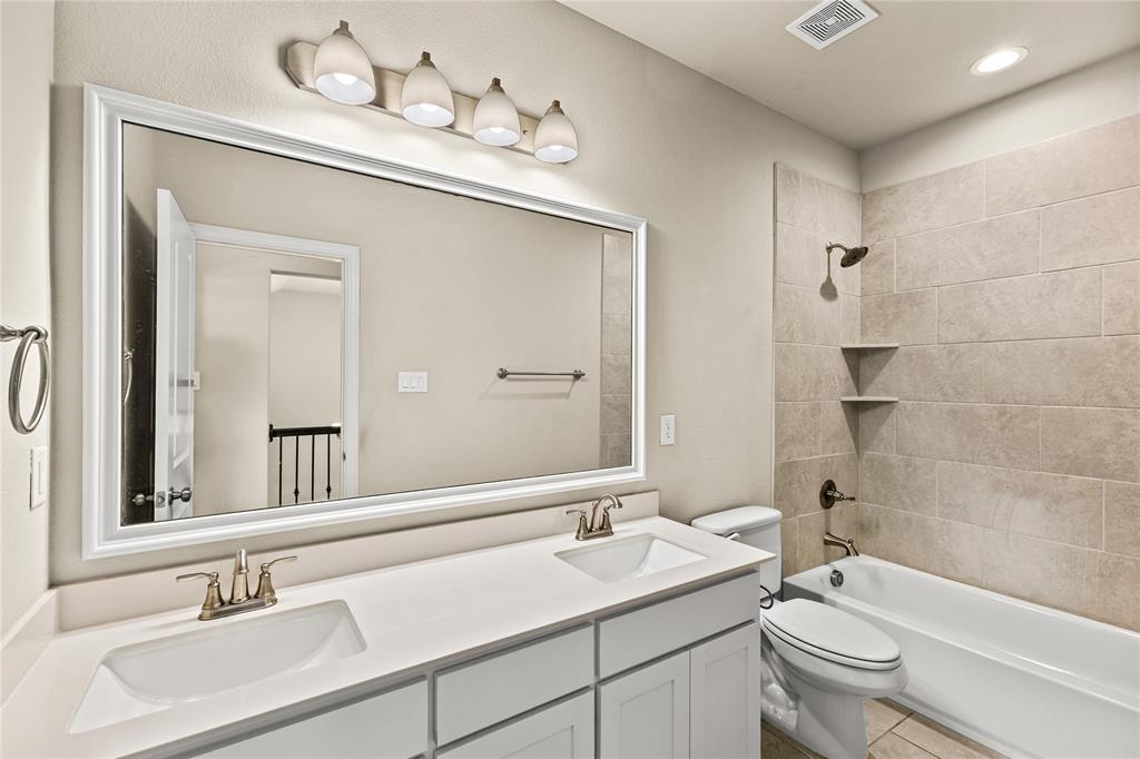 Dual-sink vanity with white cabinetry, rectangular under-mount sinks, large wall-mounted mirror, and tile-surround shower and tub combination