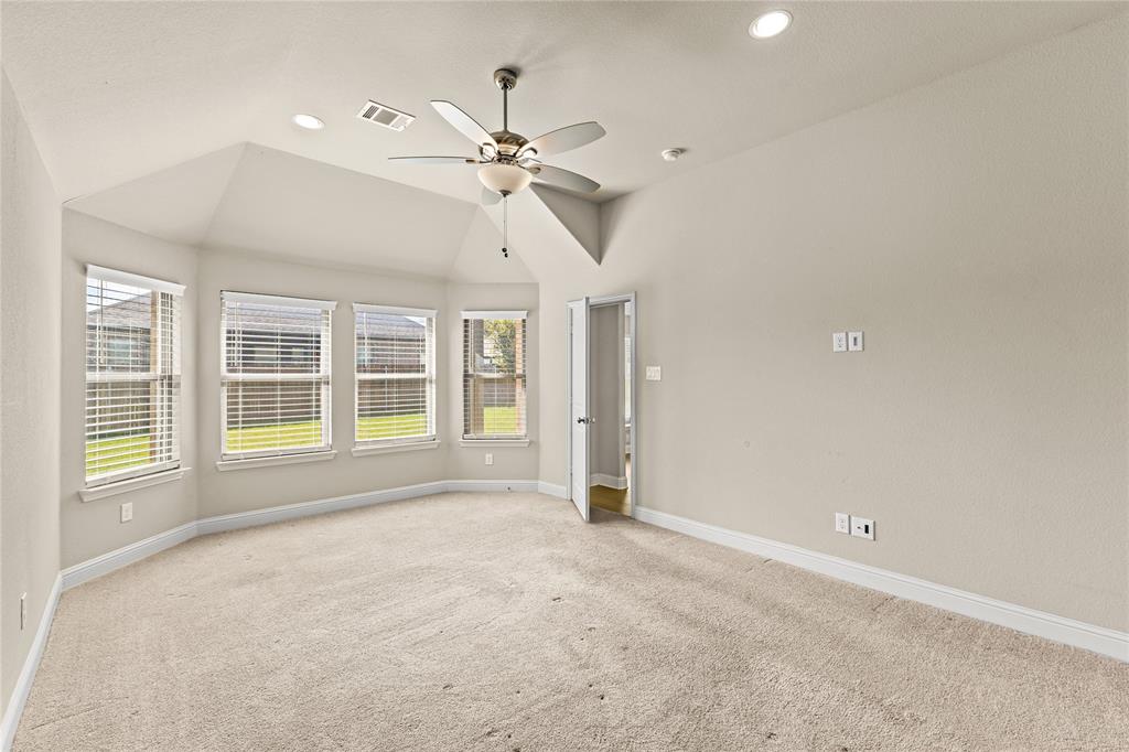 Vaulted ceiling with a centrally mounted ceiling fan, neutral wall-to-wall carpeting, multiple windows providing natural light, and recessed lighting