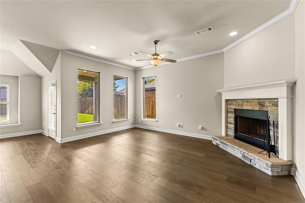 Living area featuring wood-finish flooring, a stone-surround fireplace with a white mantel, neutral wall color, recessed lighting, and a ceiling fan