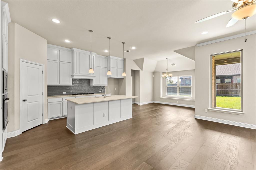 Kitchen featuring white cabinetry, center island with stone-finish countertop, dark subway tile backsplash, recessed lighting, and wood-finish flooring
