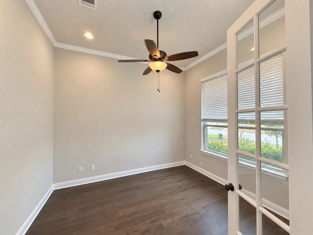 Room featuring wood-finish flooring, crown molding, recessed lighting, a ceiling fan with integrated light fixture, and French doors