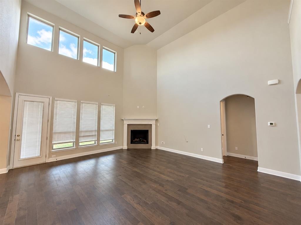 Expansive living area featuring vaulted ceilings, wood-finish flooring, a corner fireplace with a neutral surround, floor-to-ceiling windows, and a ceiling fan