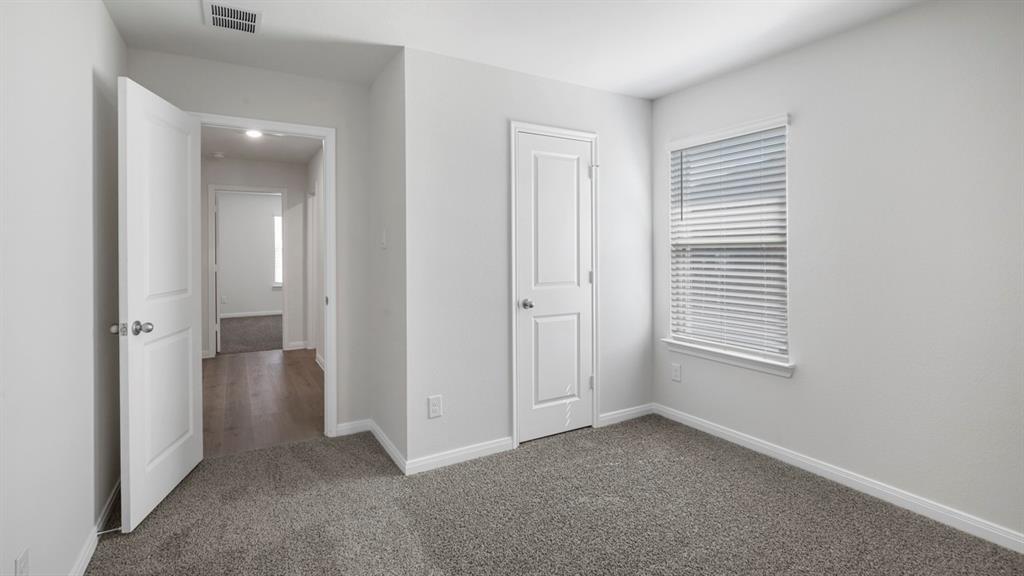 Carpeted room featuring a single window with blinds, white trim, and a white six-panel door
