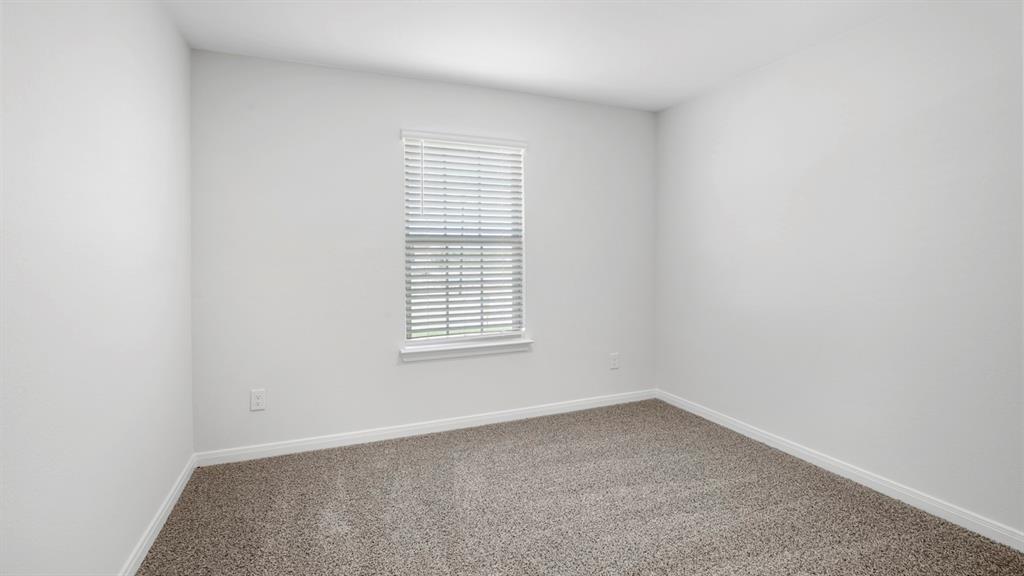 Neutral-toned carpeted room featuring a single window with blinds, white trim, and light-colored walls