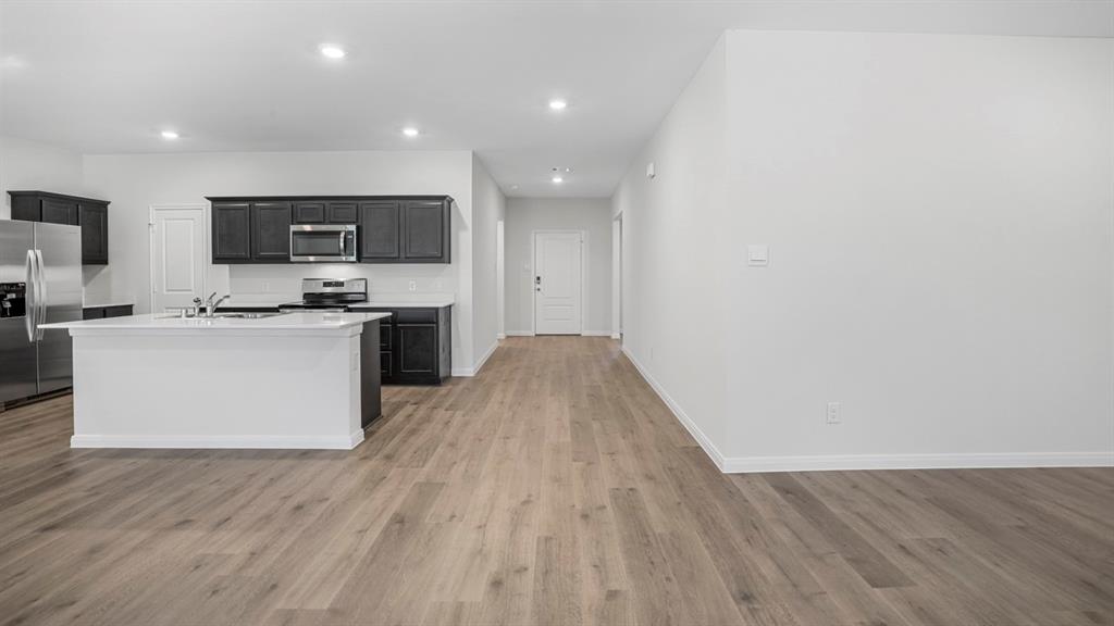 Open-concept living area featuring wood-finish flooring, recessed lighting, and a white kitchen island