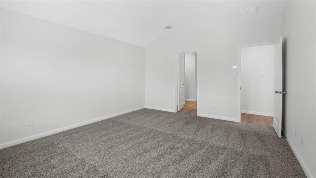 Spacious interior room featuring light gray carpeting, neutral wall finishes, white baseboards, and two doorways