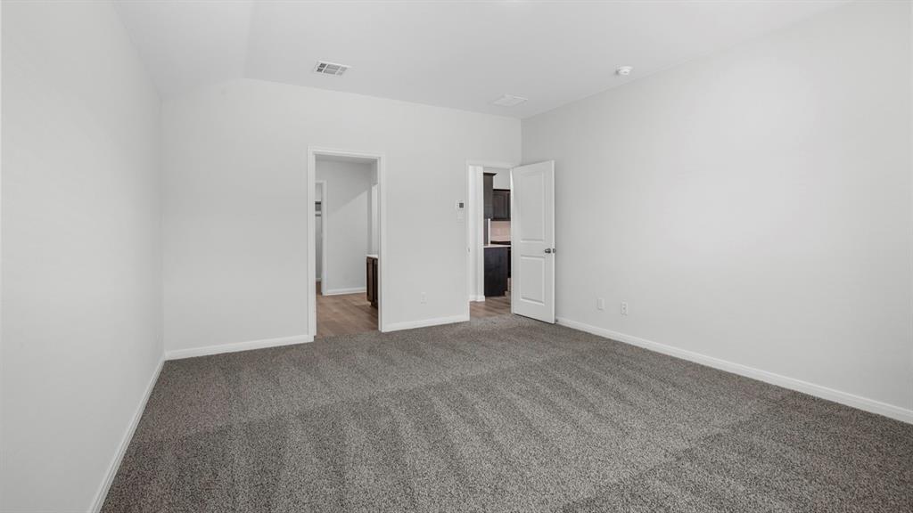 Spacious room featuring neutral carpeting, light-toned walls, and white trim