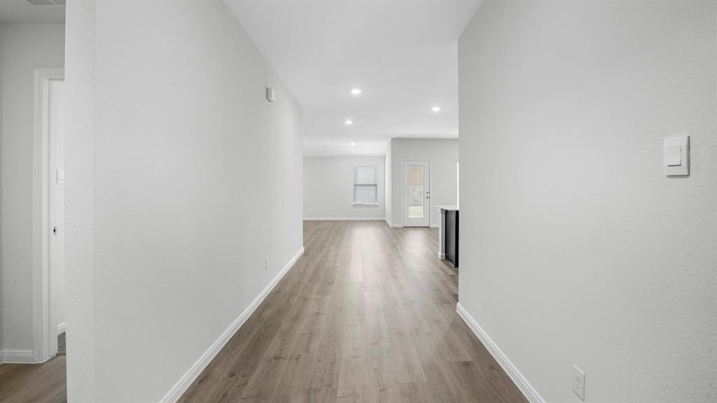 Expansive hallway featuring wood-finish flooring, recessed lighting, and crisp white walls