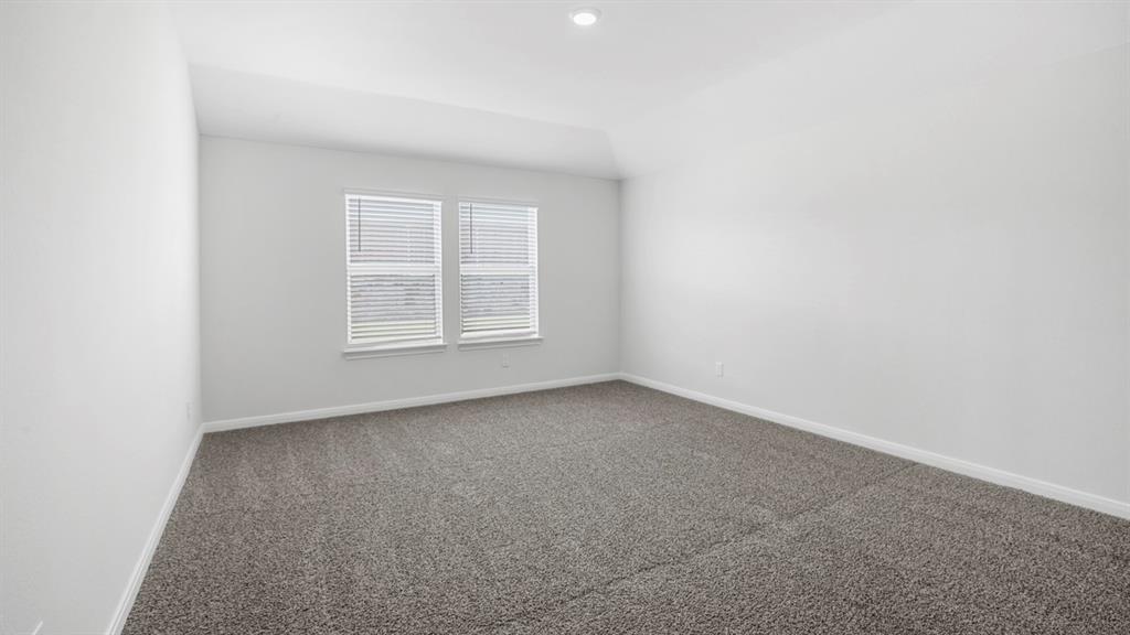 Spacious room featuring gray carpet, white walls, and a vaulted ceiling with a recessed light fixture