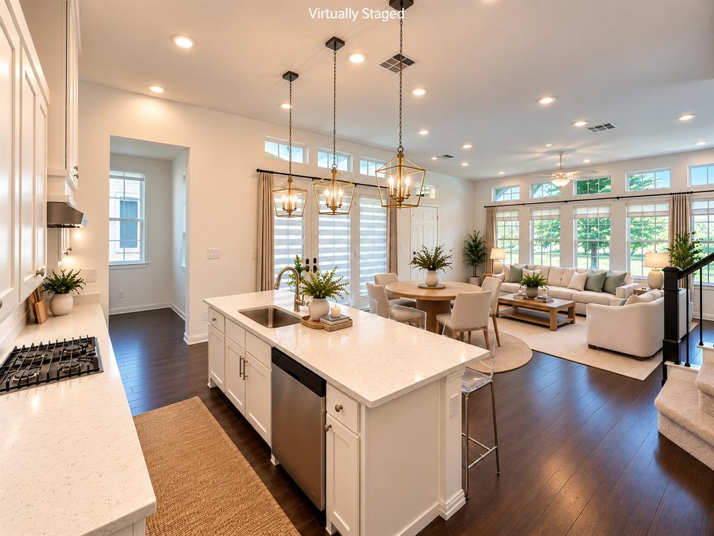 White cabinetry, large center island, quartz-look countertops, gas cooktop, stainless steel appliances, and pendant lighting.