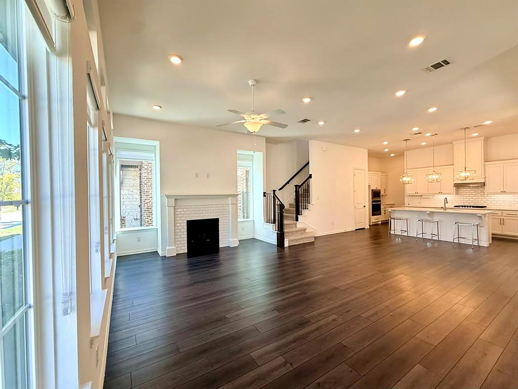 Open-concept floor plan, high ceilings, large windows, dark grand flooring, and a fireplace.