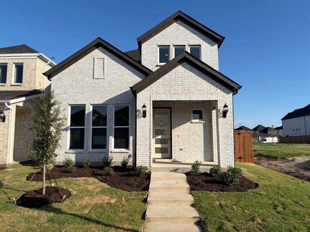 Light brick exterior featuring dark trim, multi-gabled roofline, covered entryway, and multi-pane front door