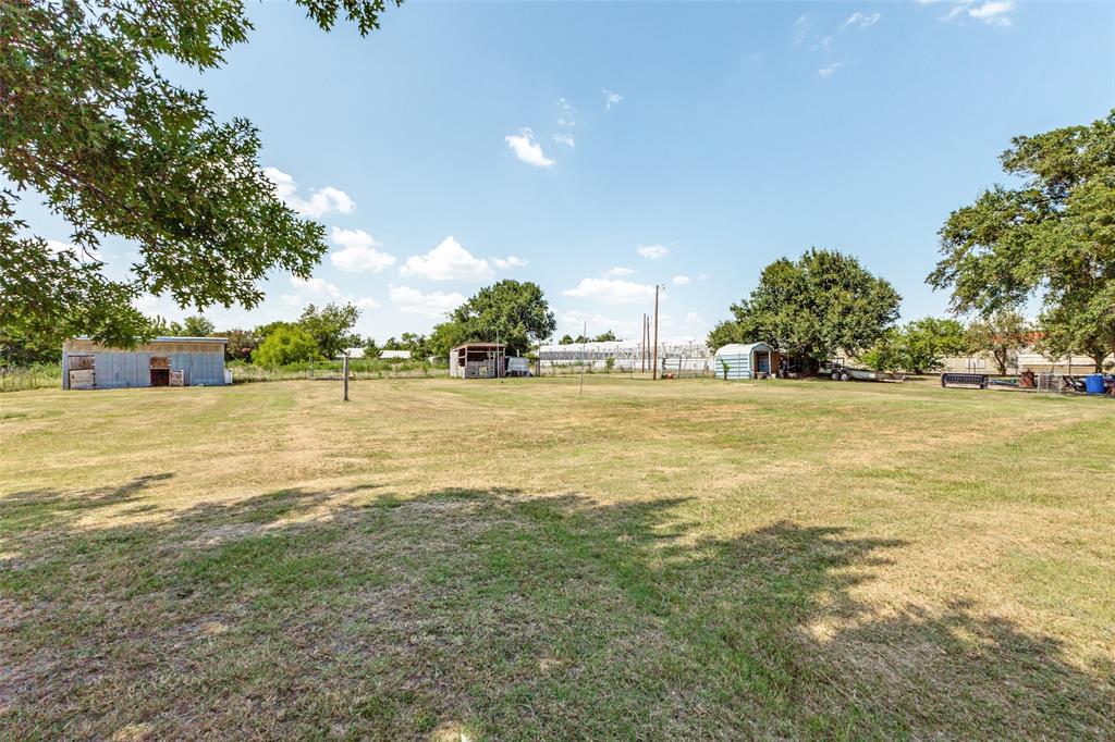 Expansive open acreage featuring mature trees, peripheral fencing, and multiple detached outbuildings