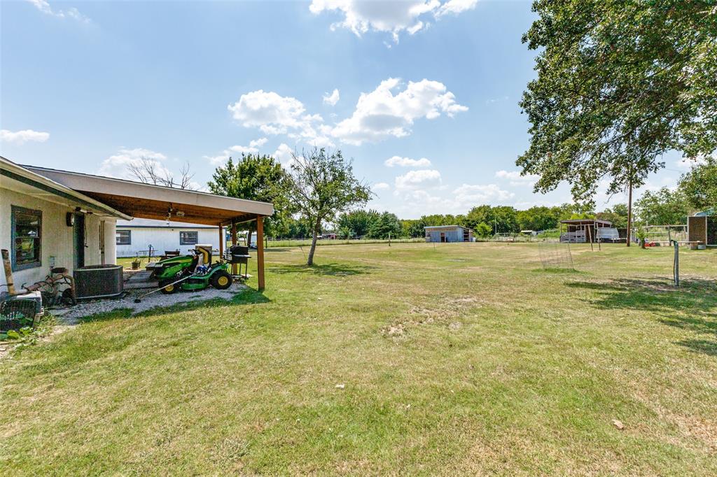 Expansive grounds featuring a covered patio, mature trees, and open green space