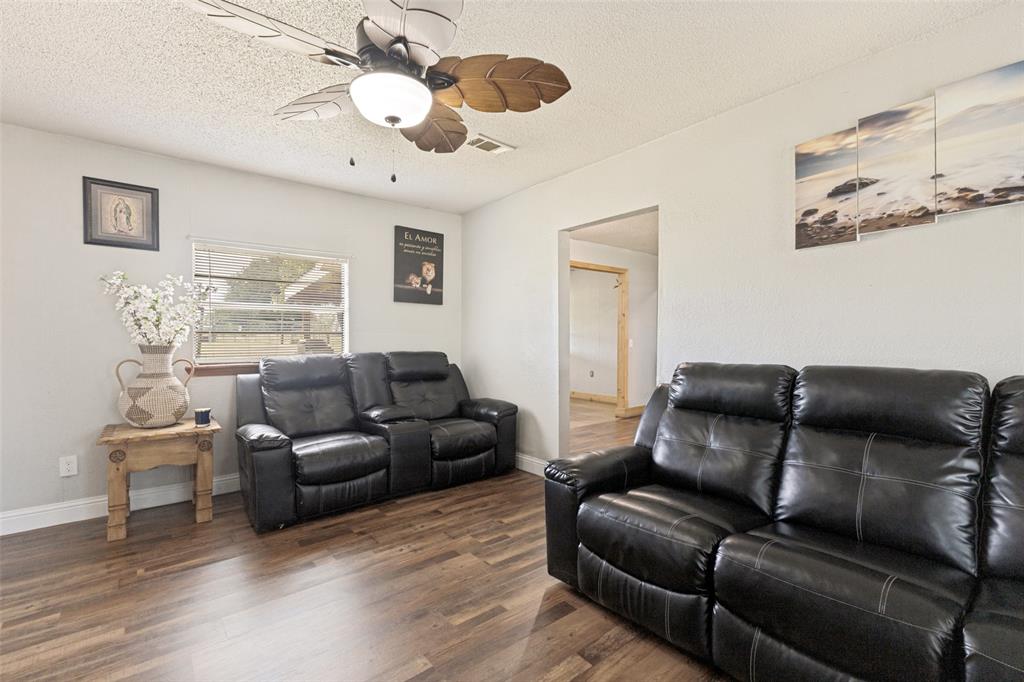 Wood-finish flooring, palm-leaf design ceiling fan with integrated lighting, and neutral-toned wall finish