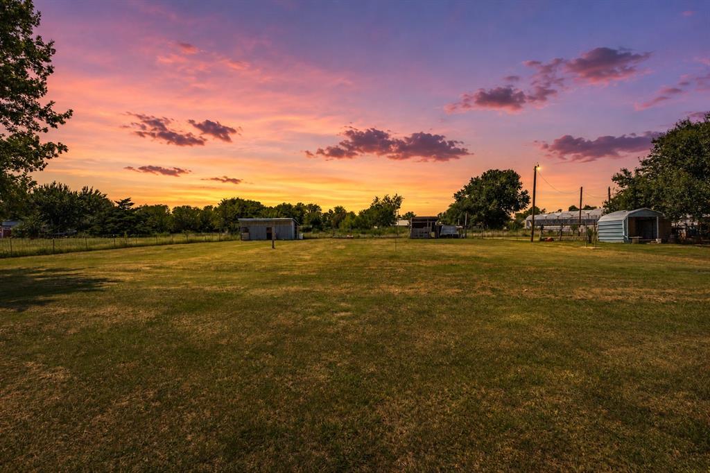 Expansive parcel featuring level terrain, mature trees, open green space, and multiple detached metal structures