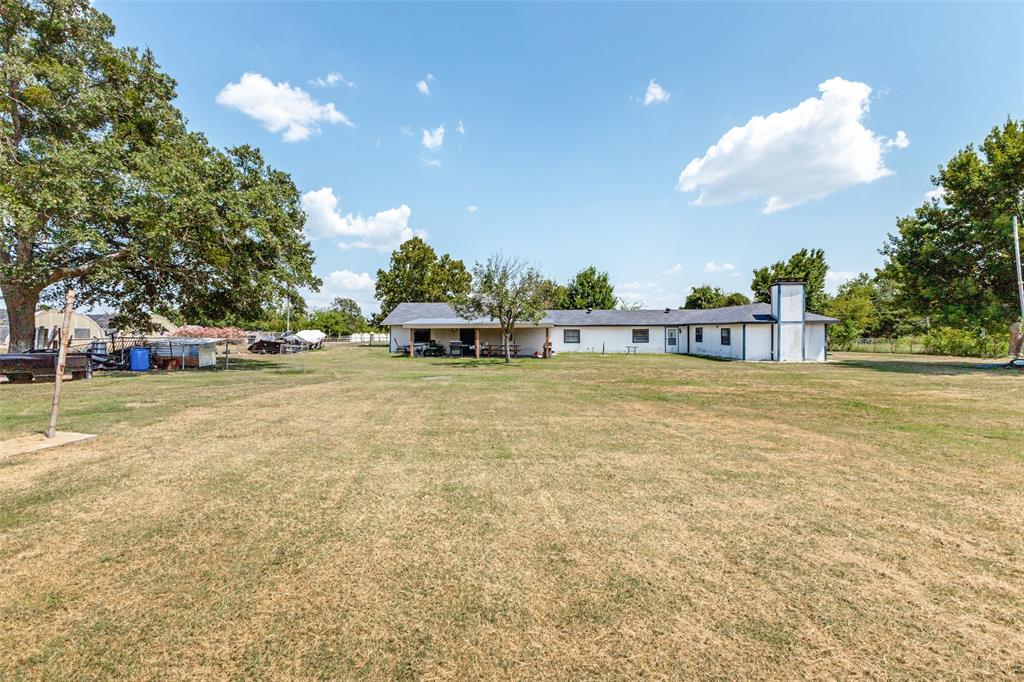 Expansive grounds featuring mature shade trees, a covered patio, and a masonry chimney